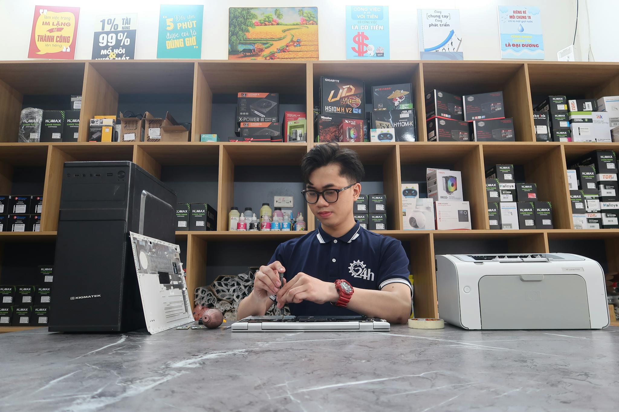 Young technician fixing a computer in a modern electronics store setting.